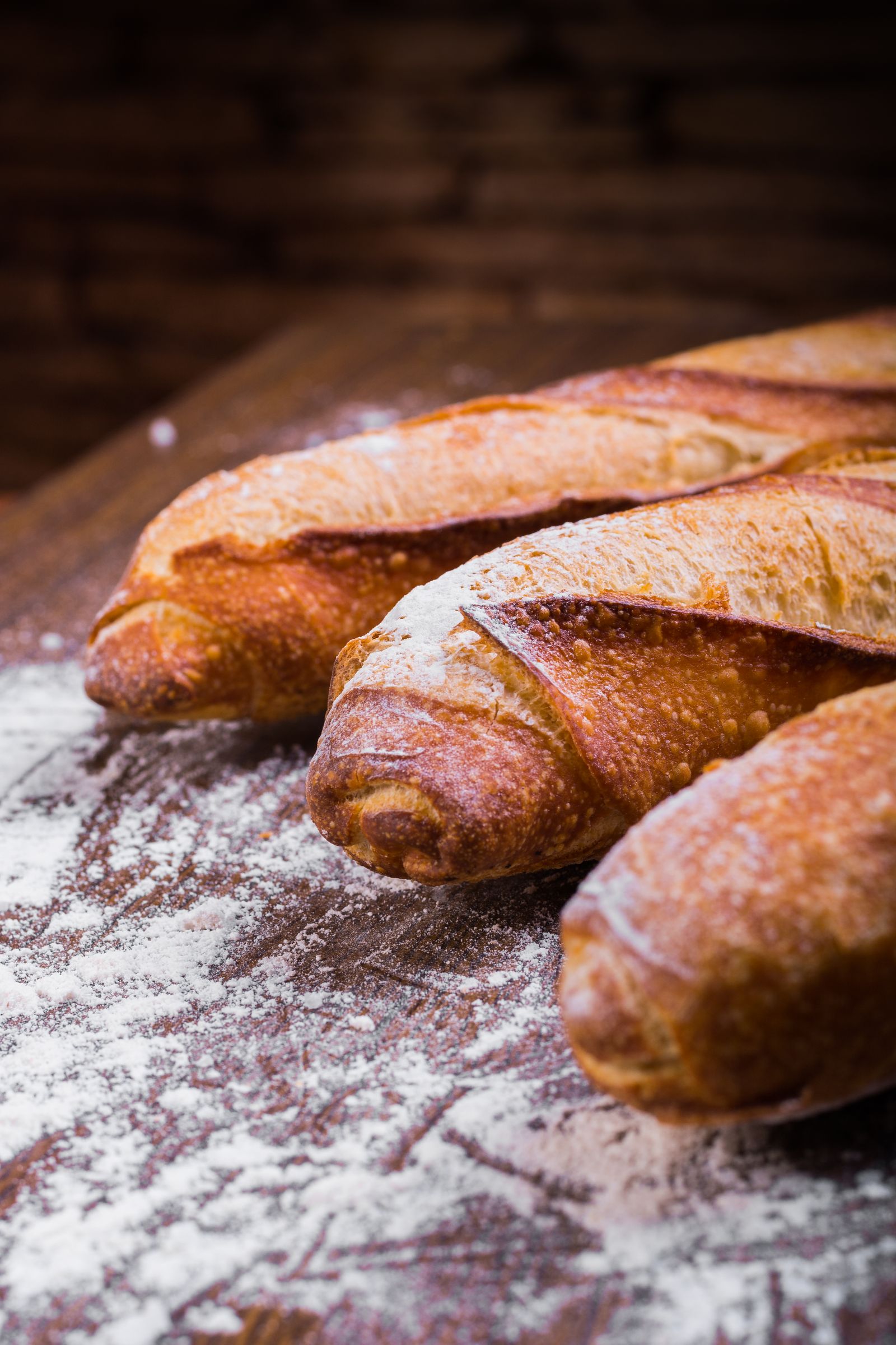 Dark crusted rye loaves dusted with flour on a scorched board