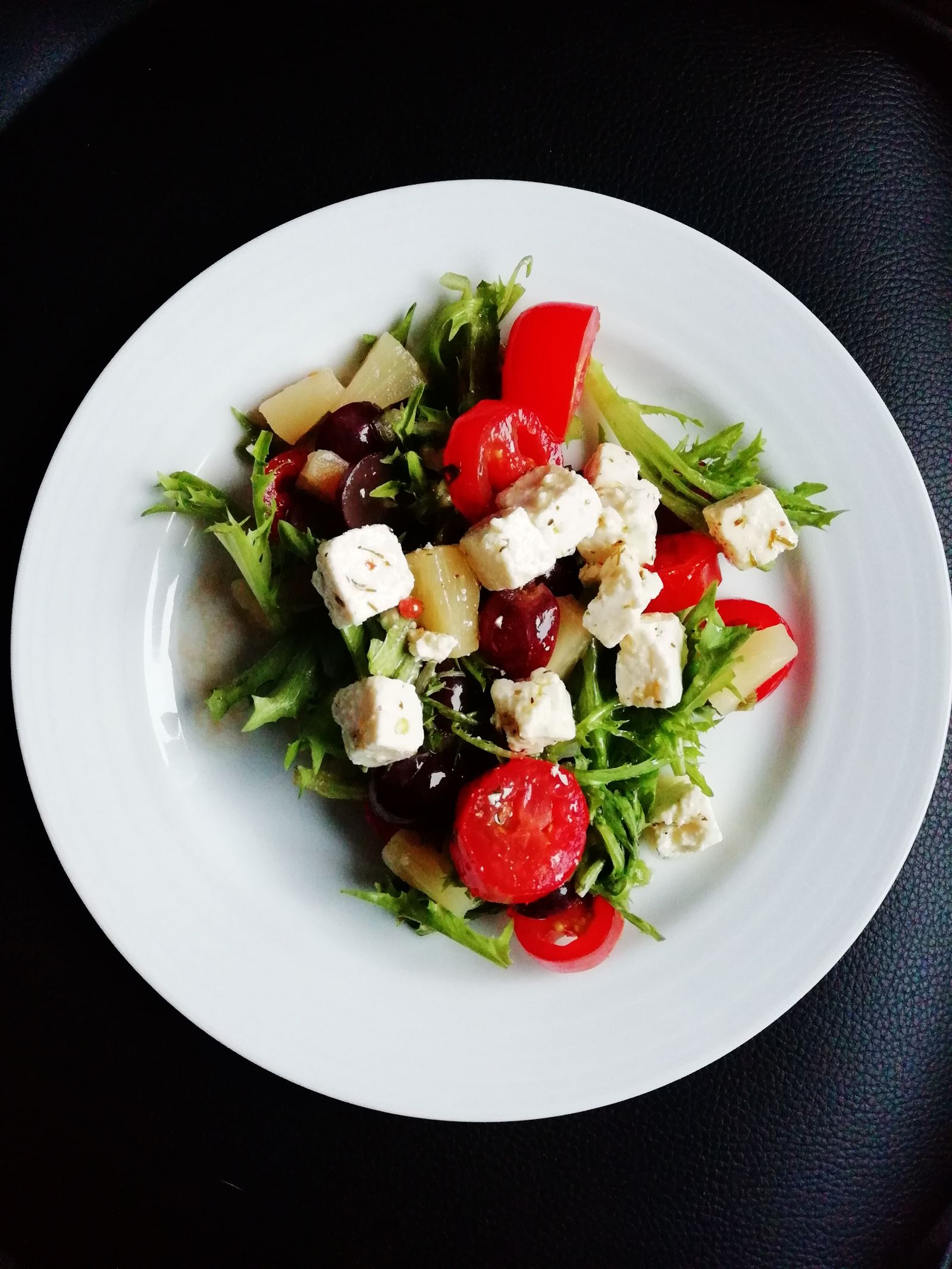 Charred leaves, smoked curd and blistered tomatoes on a dark plate
