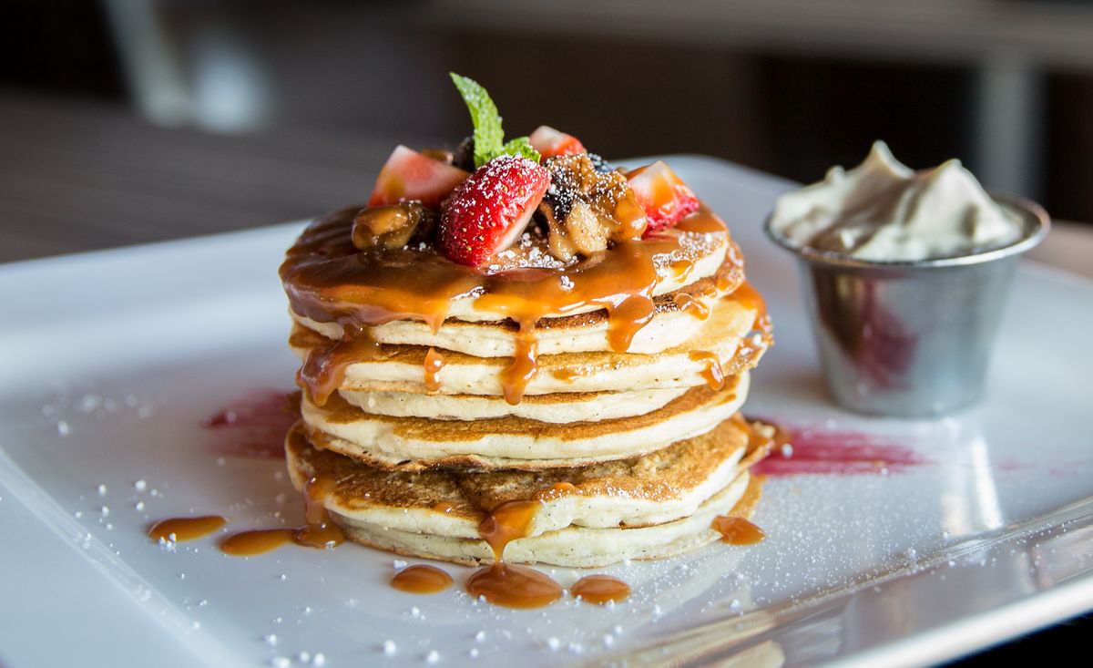 Stack of griddle cakes with caramel, strawberries and cream