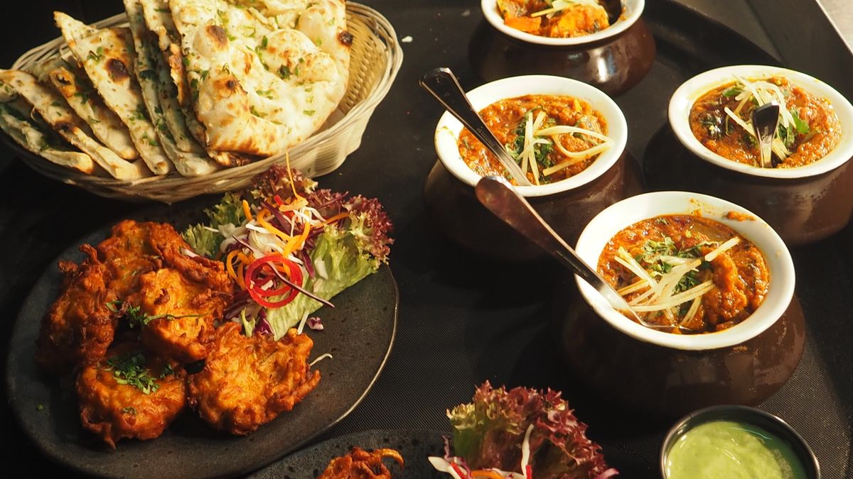 Clay pots of slow-cooked stew beside hearth flatbreads and fritters