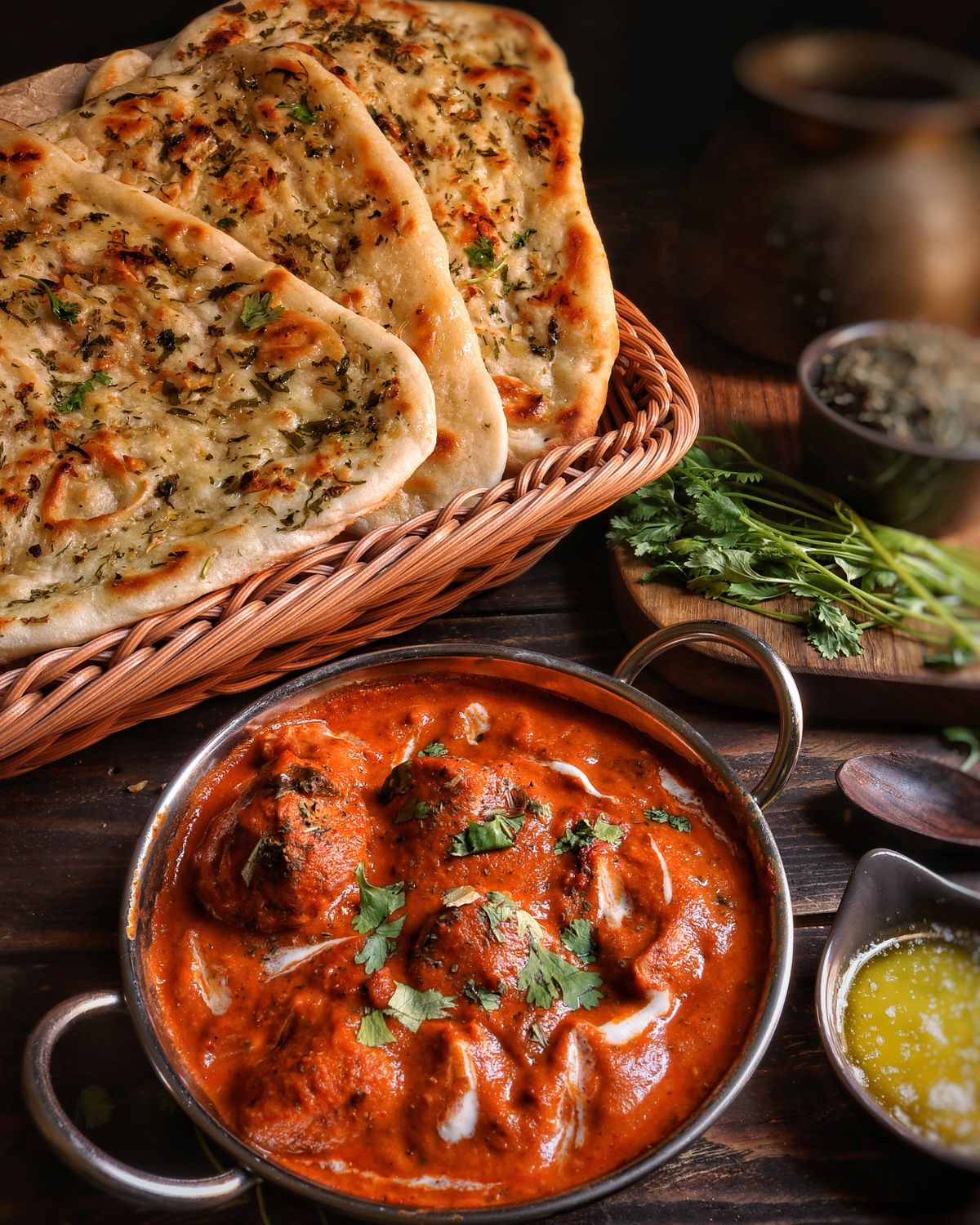 Hearth flatbreads in a basket beside a copper pot of butter stew