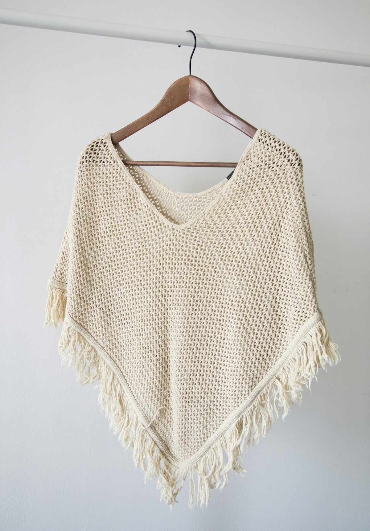 Cream open-knit fringe piece on wooden hanger