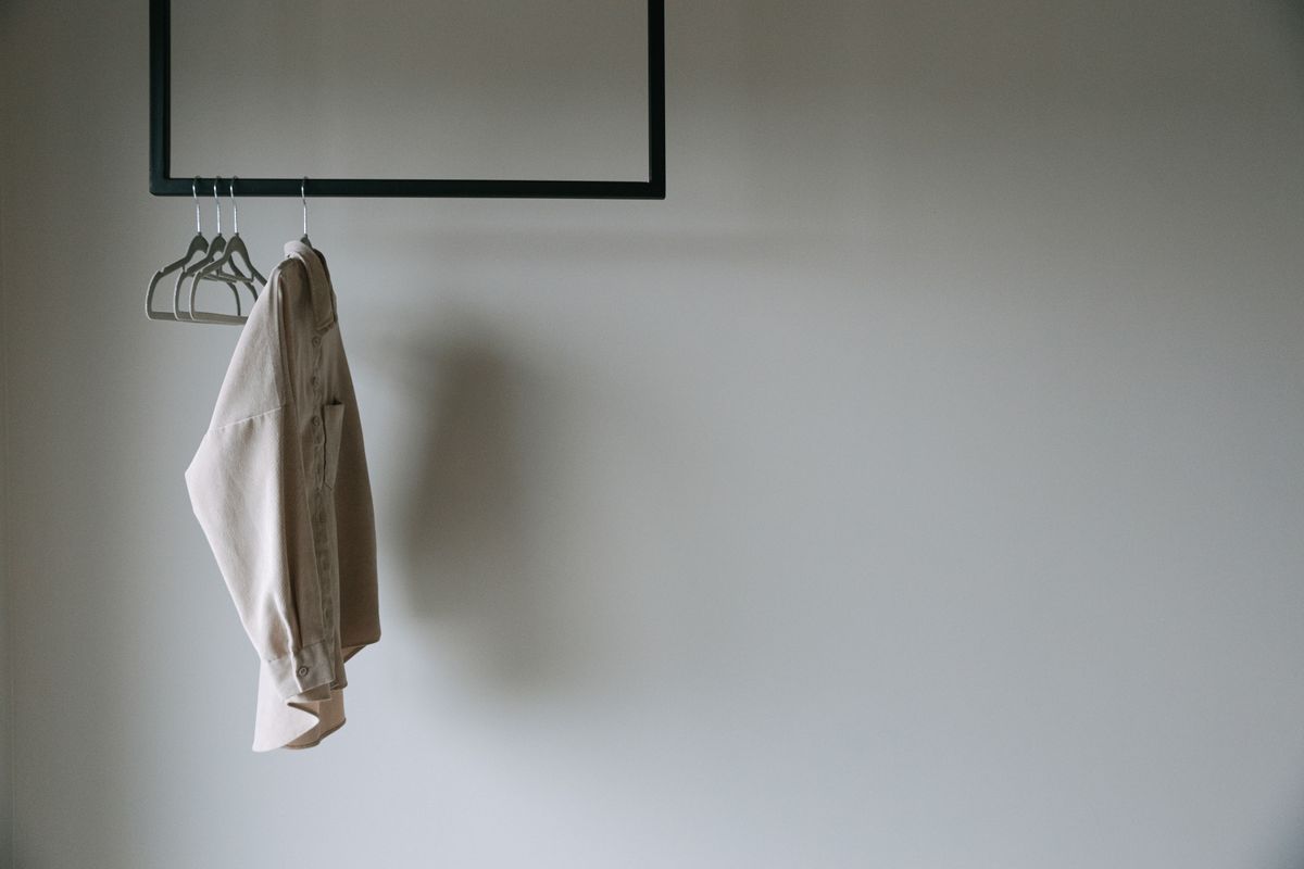 Beige shirt on black metal rack with empty hangers