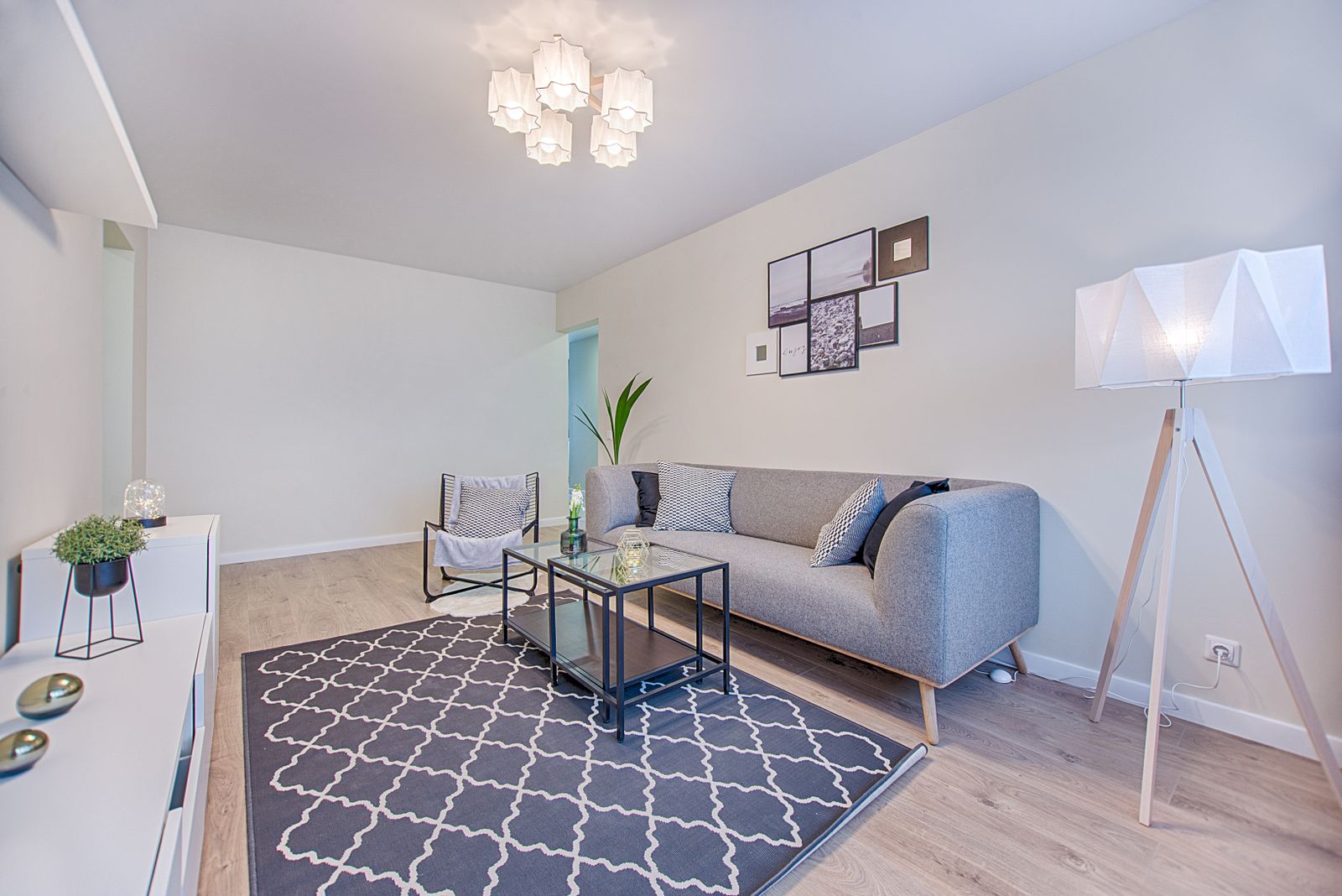 Bright living room with sofa, glass tables, and paper lamp