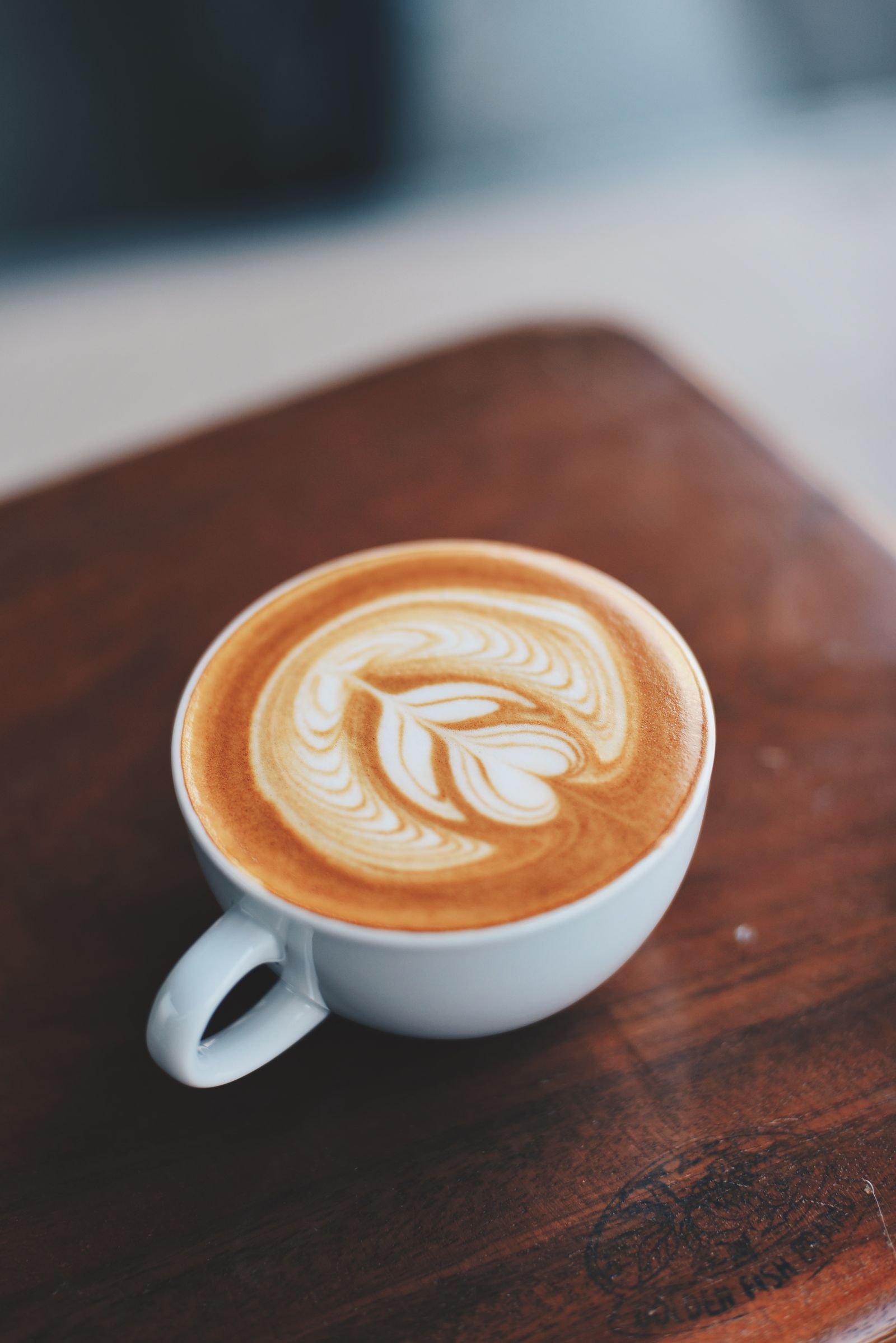 Latte art in ceramic cup on dark wood