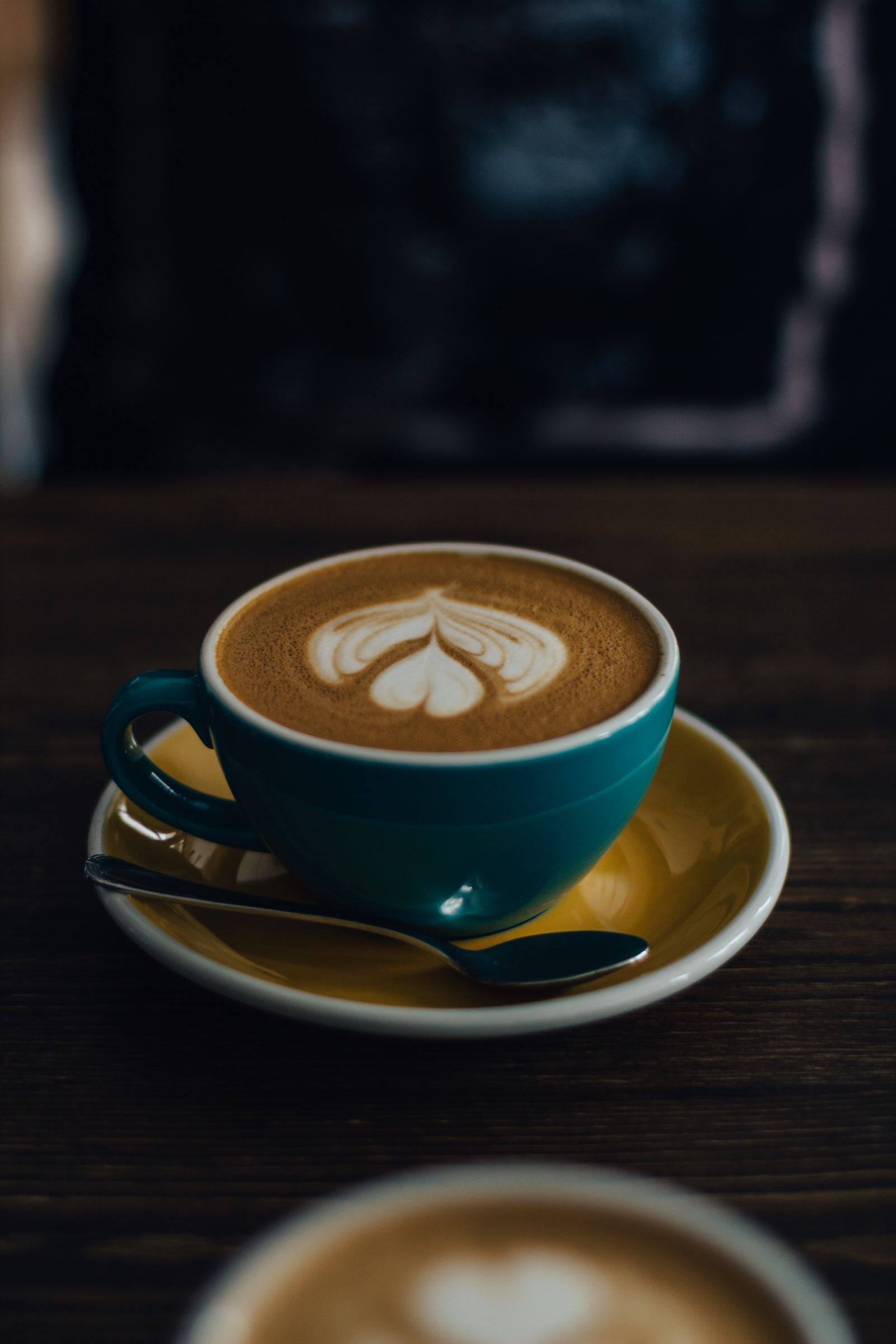 Cappuccino with heart latte art on yellow saucer