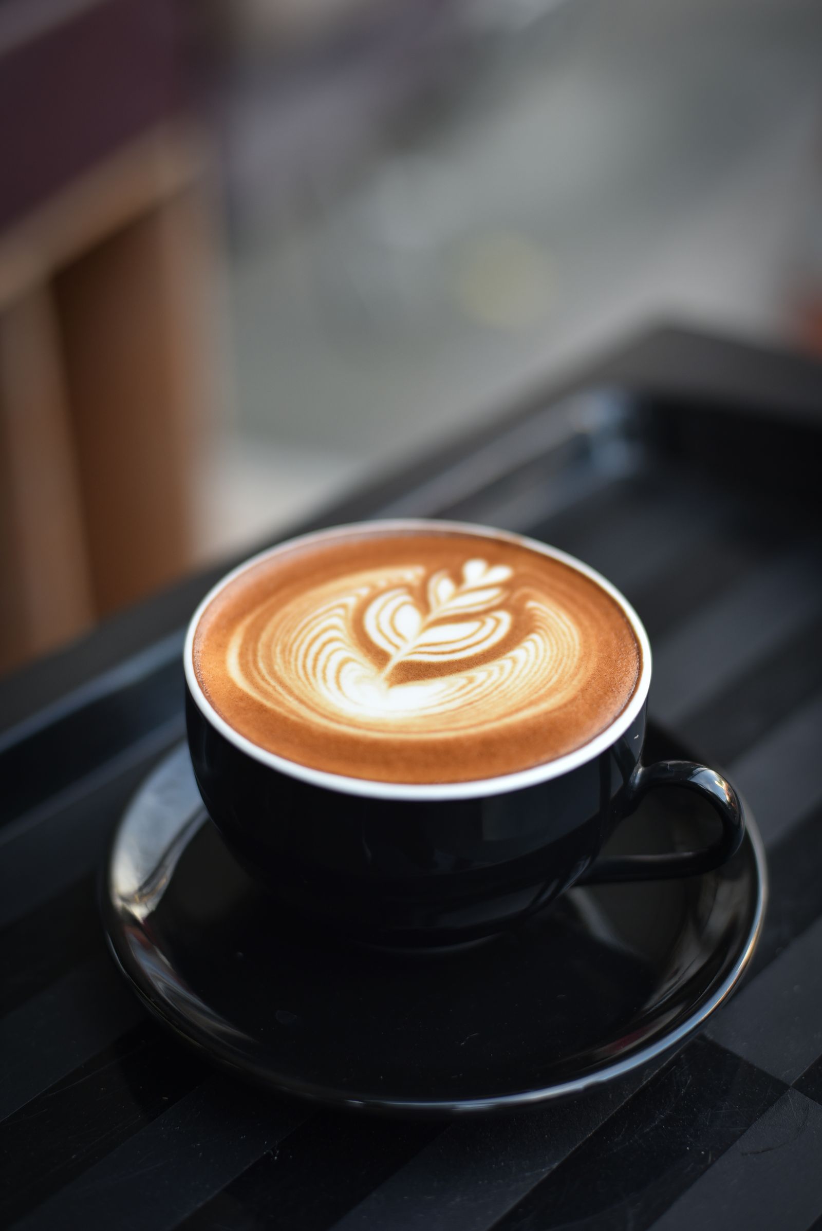 Latte with classical latte art in dark ceramic cup